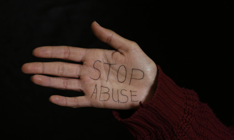 Mão de mulher com as palavras "Stop Abuse" escritas na palma contra o abuso sexual.
