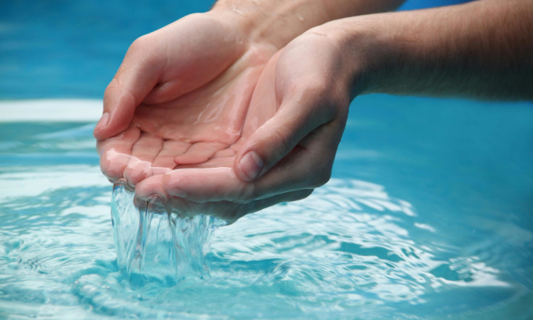 Mãos de homem em concha com água numa técnica de como controlar a ansiedade.