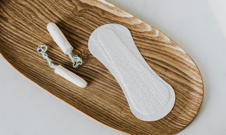 Penso higiénico e dois tampões em cima de tábua castanha para assinalar a pobreza menstrual.