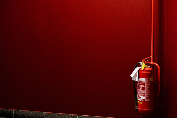 Extintor numa parede vermelha que representa a Profilaxia P&oacute;s-Exposi&ccedil;&atilde;o