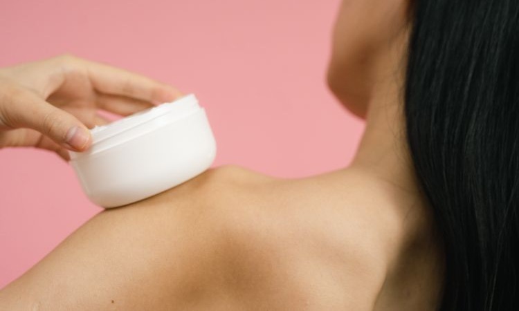 mulher segura sobre o ombro creme hidratante para cuidar da barreira cutânea danificada