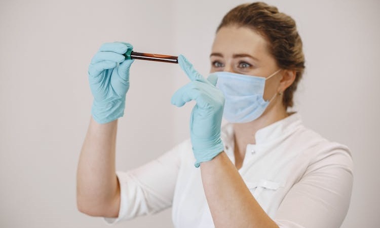 profissional de enfermagem usando EPI segura tubo de sangue para análise nas mãos