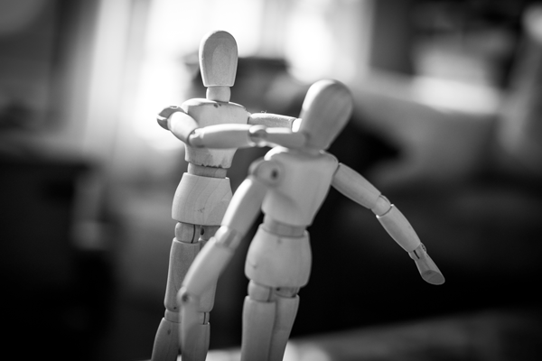 Dois bonecos de madeira onde um boneco est&aacute; a estrangular o outro representando viol&ecirc;ncia domestica 