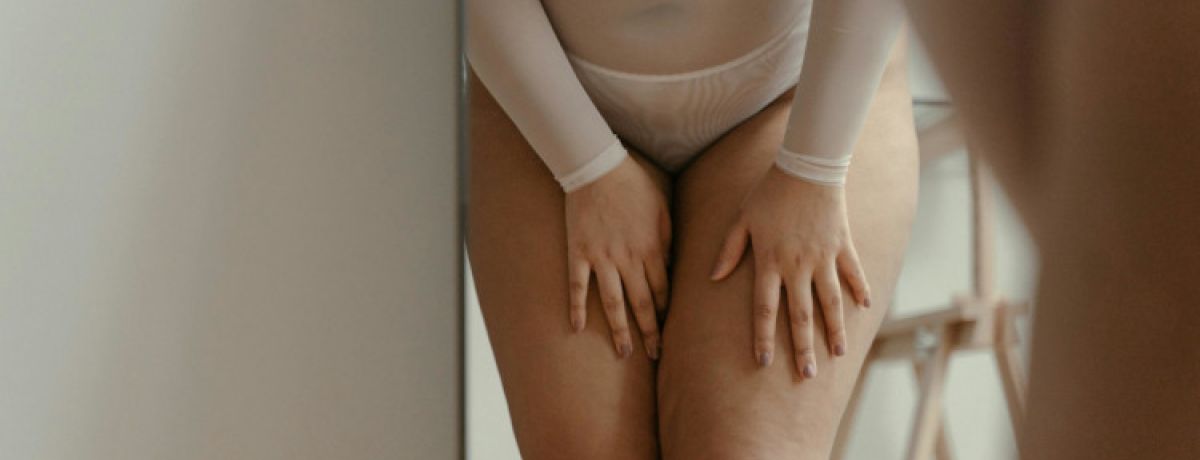 Tronco de mulher gordinha de cuecas grandes brancas a tocar nas suas pernas nuas com sintomas de candidíase.