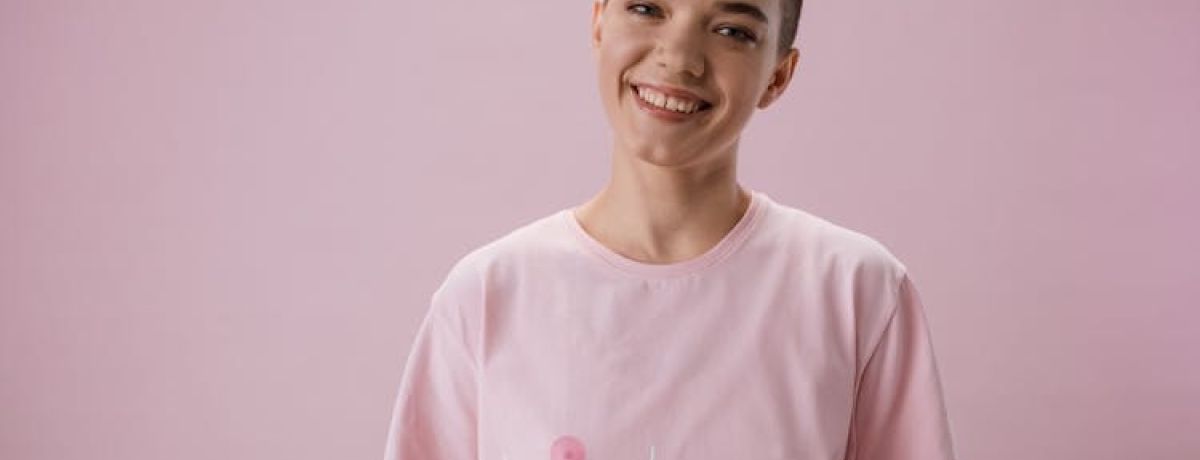 mulher transgénero sorri, vestindo uma camisola rosa