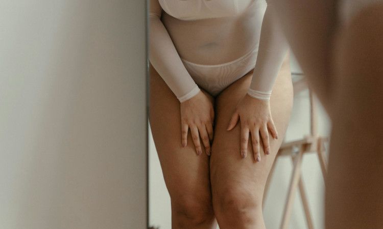 Tronco de mulher gordinha de cuecas grandes brancas a tocar nas suas pernas nuas com sintomas de candidíase.