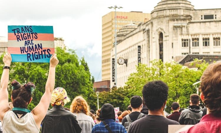 pessoa segura cartaz pela defesa dos direitos trans em manifestação de rua