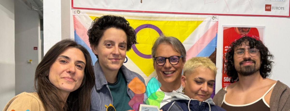 Equipa de cinco técnicos do GAT, incluindo Júlio Esteves de óculos, a sorrir e a segurar Prémio AproXima-te com cartaz em cima a dizer "Trabalho Sexual é trabalho".