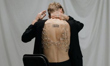 pessoa de costas, mão no pescoço, com tatuagem a dizer freedom nas costas