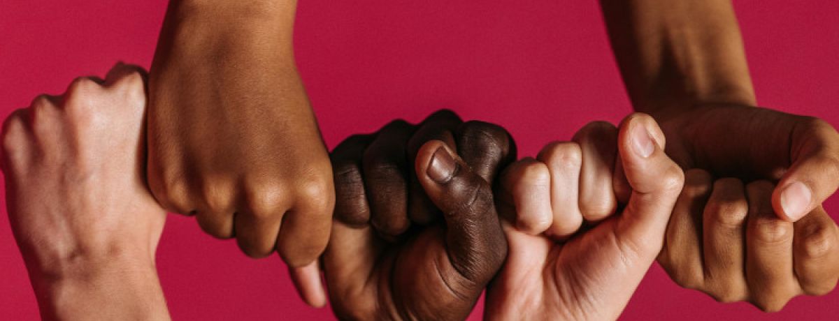Mãos de cores diferentes de punho cerrado, colocadas lado a lado para representar a justiça social.