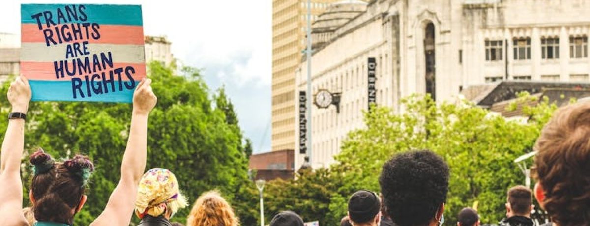 pessoa segura cartaz pela defesa dos direitos trans em manifestação de rua