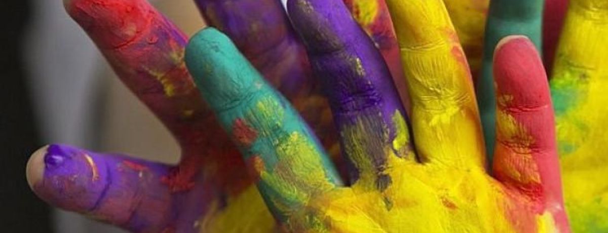 Mãos pintadas de várias cores para simbolizar a linguagem inclusiva