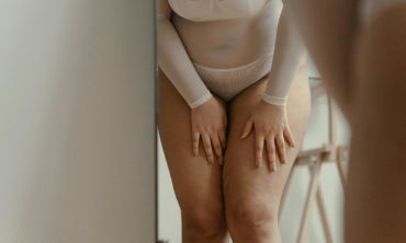 Tronco de mulher gordinha de cuecas grandes brancas a tocar nas suas pernas nuas com sintomas de candidíase.