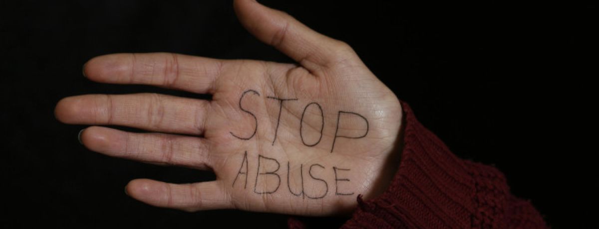 Mão de mulher com as palavras "Stop Abuse" escritas na palma contra o abuso sexual.
