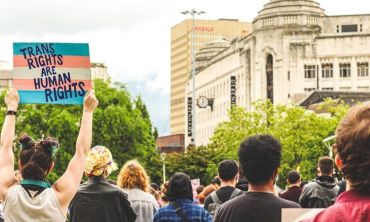 pessoa segura cartaz pela defesa dos direitos trans em manifestação de rua