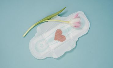 Penso branco com coração rosa feito de renda recortado em cima e uma tulipa rosa com a flor em cima numa representação da dignidade menstrual.