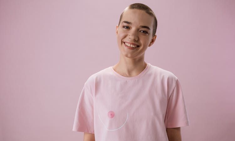 mulher transgénero sorri, vestindo uma camisola rosa