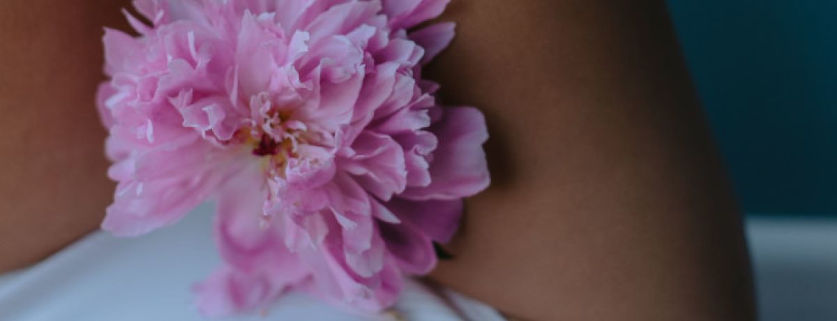 Mulher de cuecas brancas com flor rosa na zona íntima a representar a menopausa.