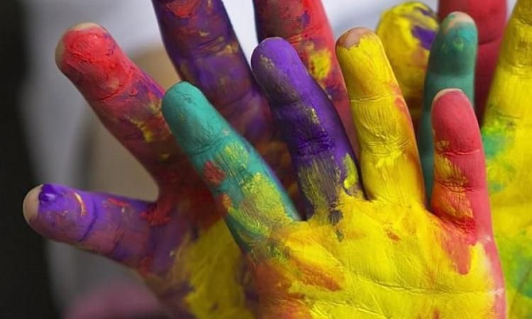 Mãos pintadas de várias cores para simbolizar a linguagem inclusiva